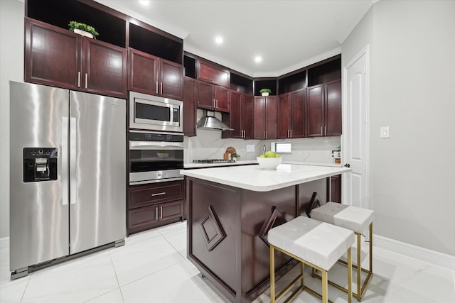 kitchen with decorative backsplash, appliances with stainless steel finishes, a kitchen island, light stone counters, and a breakfast bar area