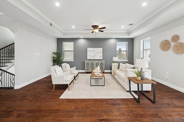 living room featuring a raised ceiling, crown molding, dark hardwood / wood-style flooring, and ceiling fan