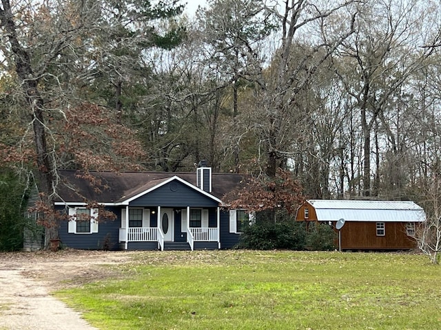 single story home with a front lawn, covered porch, and a storage shed