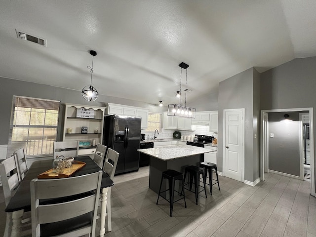 kitchen featuring white cabinetry, a kitchen island, lofted ceiling, and black appliances