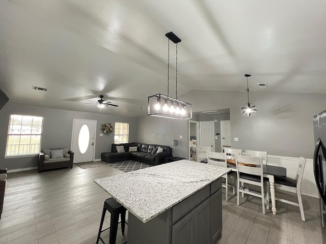 kitchen with hardwood / wood-style floors, a center island, hanging light fixtures, and lofted ceiling