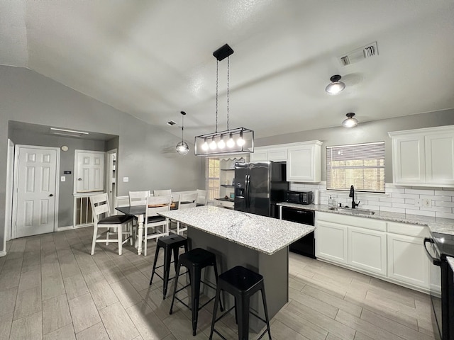 kitchen featuring black appliances, sink, hanging light fixtures, a kitchen island, and white cabinetry