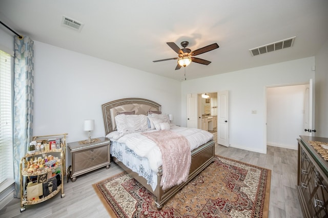 bedroom featuring light wood-type flooring, ceiling fan, and ensuite bath