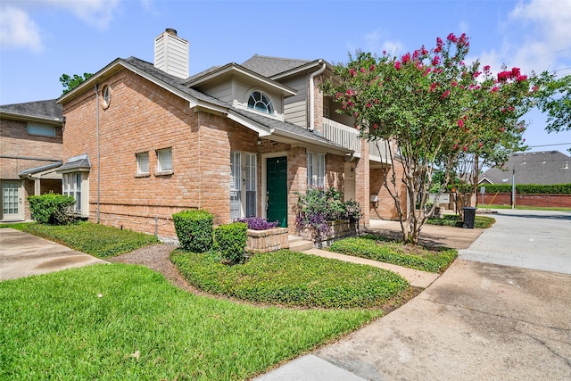 view of front of house with a front yard and a balcony