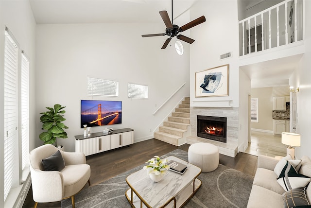 living room with dark hardwood / wood-style flooring, ceiling fan, high vaulted ceiling, and a high end fireplace