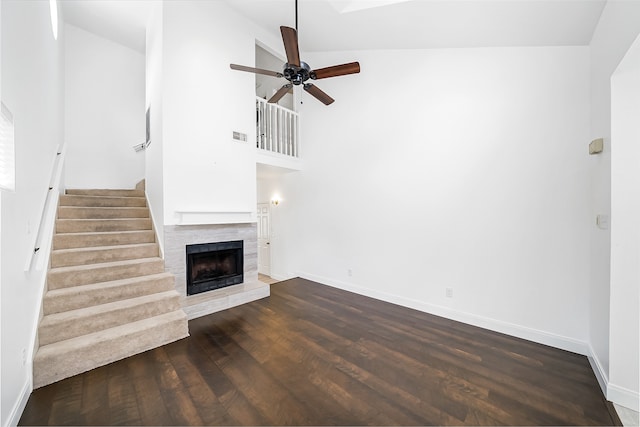 unfurnished living room featuring a fireplace, dark hardwood / wood-style floors, ceiling fan, and high vaulted ceiling