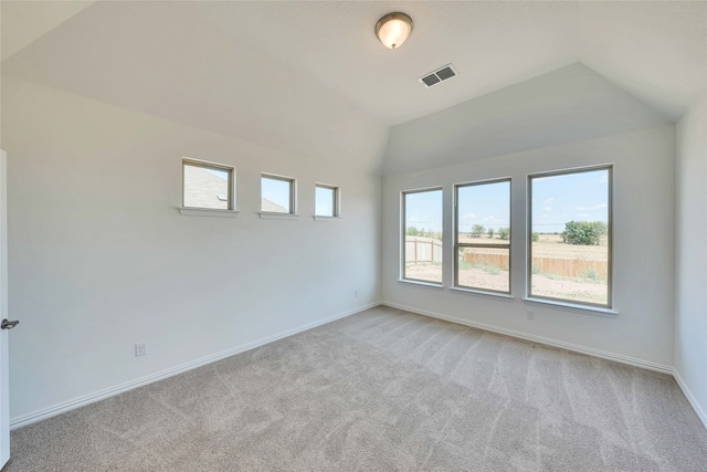 carpeted empty room with lofted ceiling