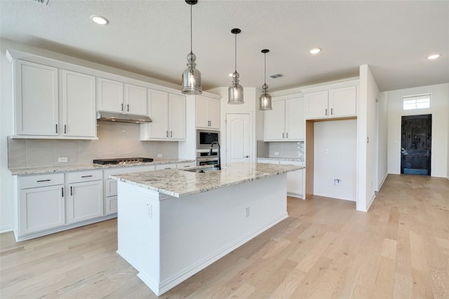 kitchen featuring white cabinets, light hardwood / wood-style floors, a center island with sink, and appliances with stainless steel finishes