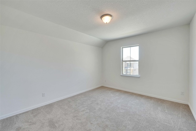 unfurnished room featuring light colored carpet, lofted ceiling, and a textured ceiling