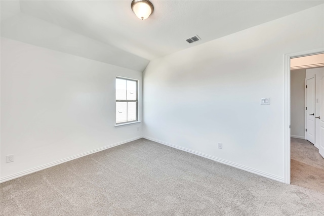 spare room with light colored carpet and vaulted ceiling