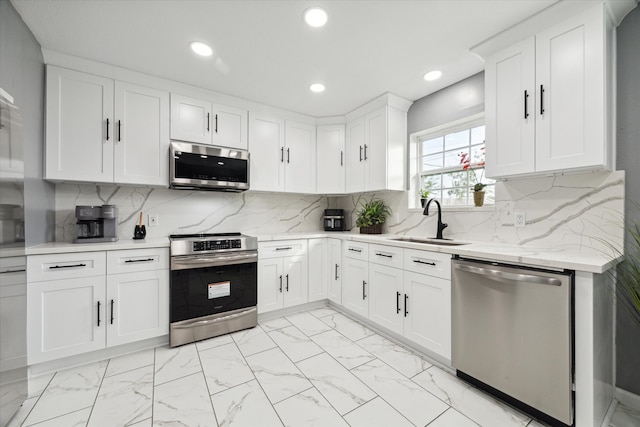 kitchen with decorative backsplash, white cabinetry, appliances with stainless steel finishes, and sink