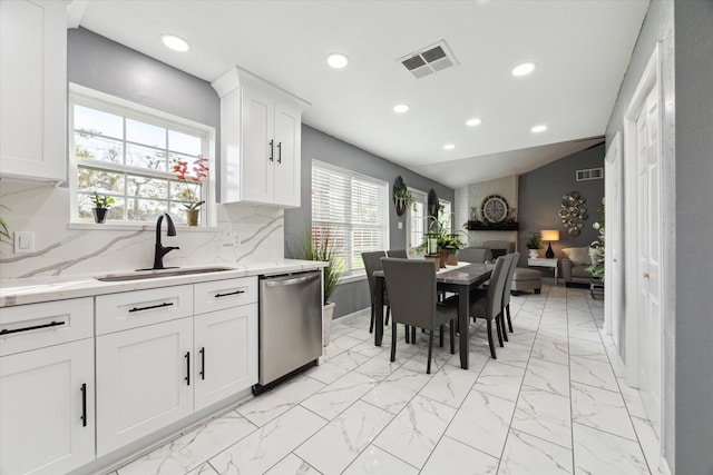 kitchen with a fireplace, backsplash, sink, dishwasher, and lofted ceiling