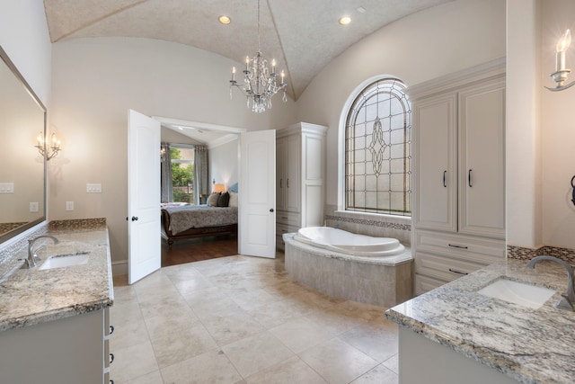 bathroom with a chandelier, vanity, lofted ceiling, and tiled tub