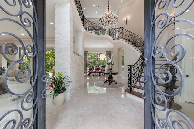 entryway with a high ceiling, crown molding, and a notable chandelier