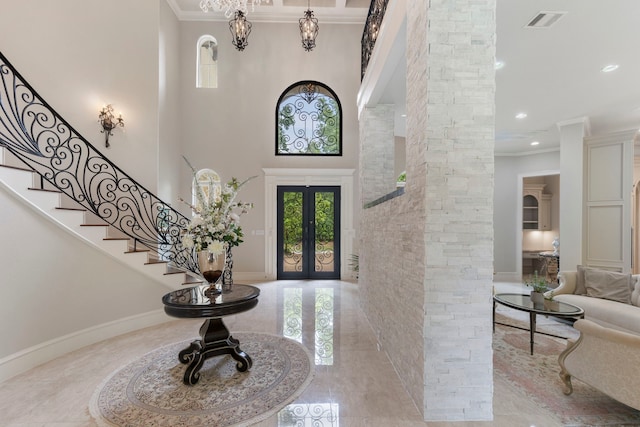 entryway featuring french doors, a towering ceiling, ornate columns, and crown molding