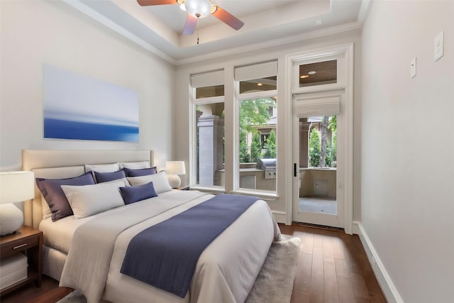 bedroom with ceiling fan, dark hardwood / wood-style floors, crown molding, and a tray ceiling