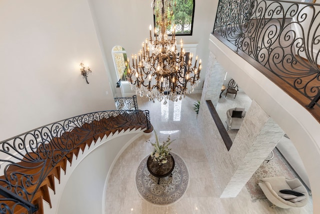 stairway featuring a high ceiling, decorative columns, and a notable chandelier