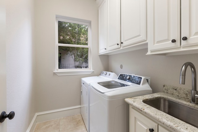 laundry room with washer and clothes dryer, light tile patterned flooring, cabinets, and sink