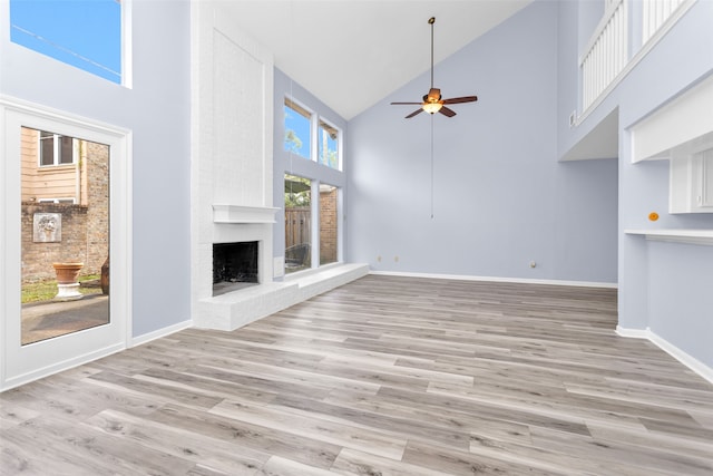 unfurnished living room with a fireplace, ceiling fan, light hardwood / wood-style flooring, and high vaulted ceiling