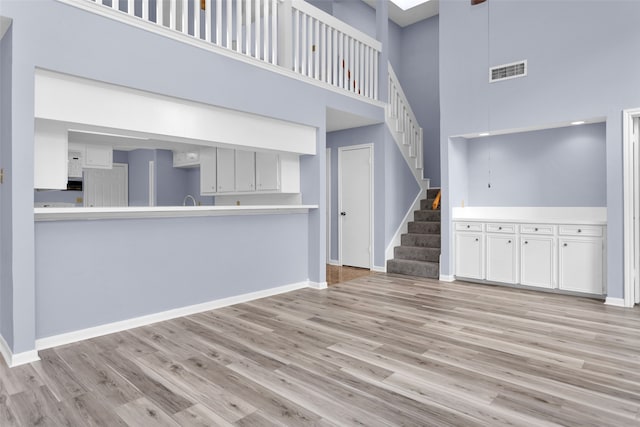 unfurnished living room with light hardwood / wood-style flooring and a towering ceiling