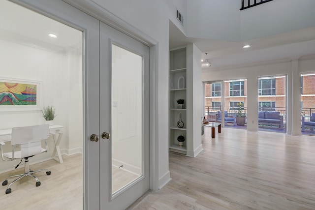 corridor with built in features, french doors, and light hardwood / wood-style floors