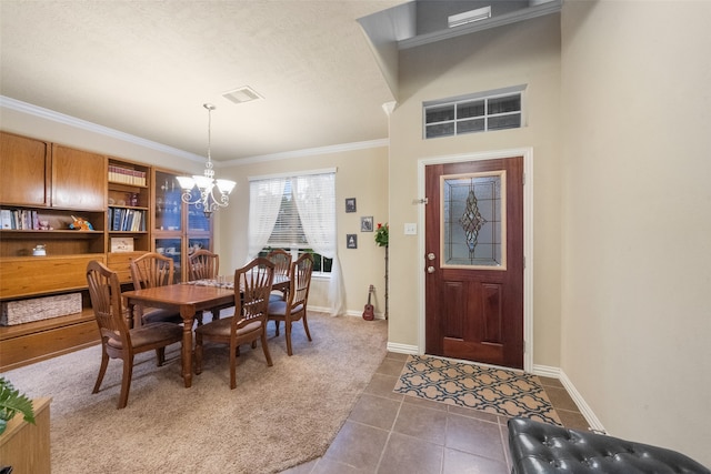 dining room featuring dark tile patterned floors, crown molding, and an inviting chandelier