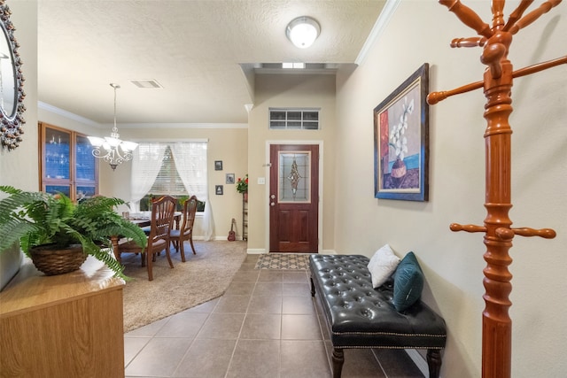 tiled entrance foyer featuring a chandelier, a textured ceiling, and ornamental molding