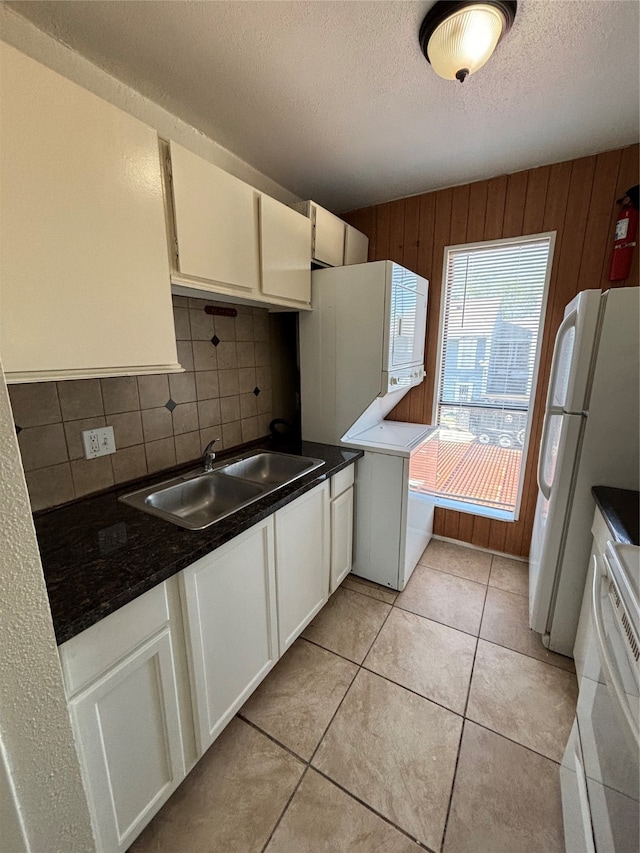 kitchen with white cabinetry, wooden walls, sink, and backsplash