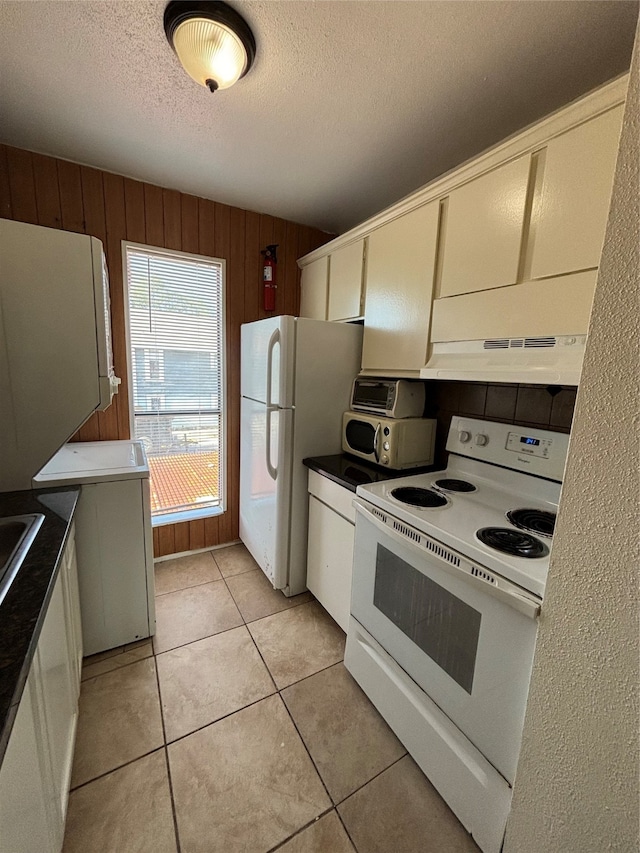 kitchen featuring wood walls, a textured ceiling, white appliances, and light tile patterned flooring