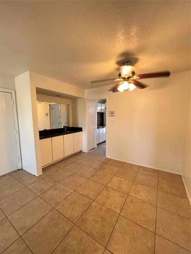 tiled spare room with sink, a textured ceiling, and ceiling fan