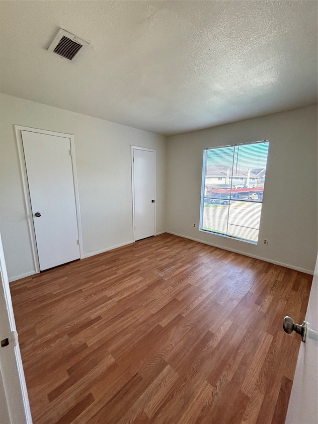 unfurnished room with a textured ceiling and hardwood / wood-style flooring