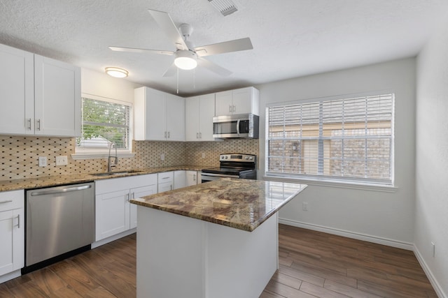 kitchen with stainless steel appliances, white cabinetry, dark wood-type flooring, and sink