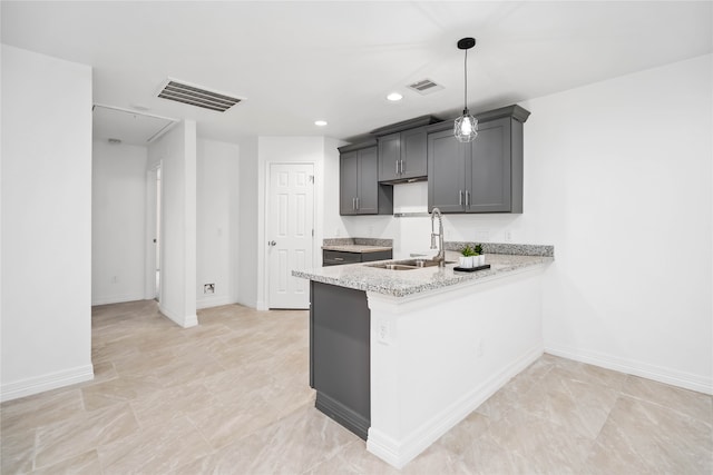 kitchen with pendant lighting, kitchen peninsula, sink, and light stone countertops