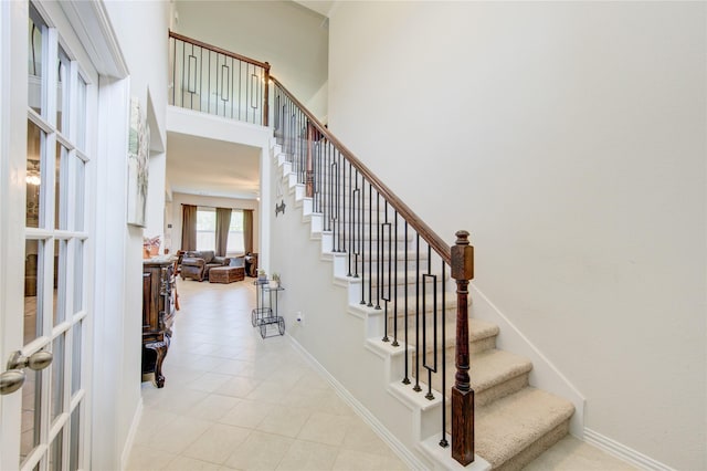 8438 Sunset Isles Dr, Baytown, TX 77521 - stairway featuring tile patterned flooring, baseboards, french doors, and a high ceiling