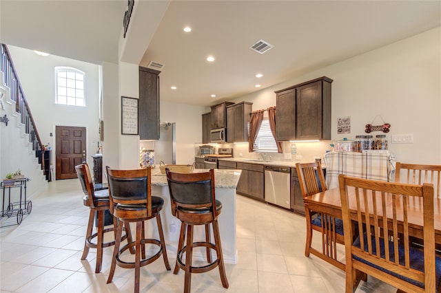 kitchen featuring dark brown cabinets, appliances with stainless steel finishes, sink, and light tile patterned floors