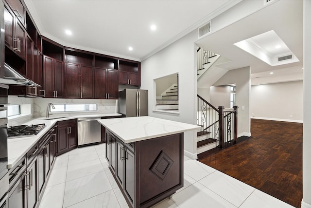 kitchen featuring sink, crown molding, backsplash, stainless steel appliances, and a kitchen island