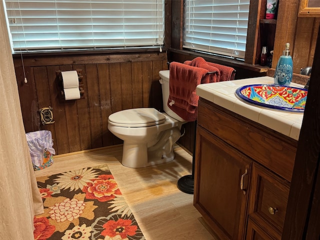 bathroom featuring hardwood / wood-style flooring, vanity, toilet, and wooden walls