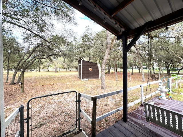 view of yard featuring a wooden deck and a storage shed