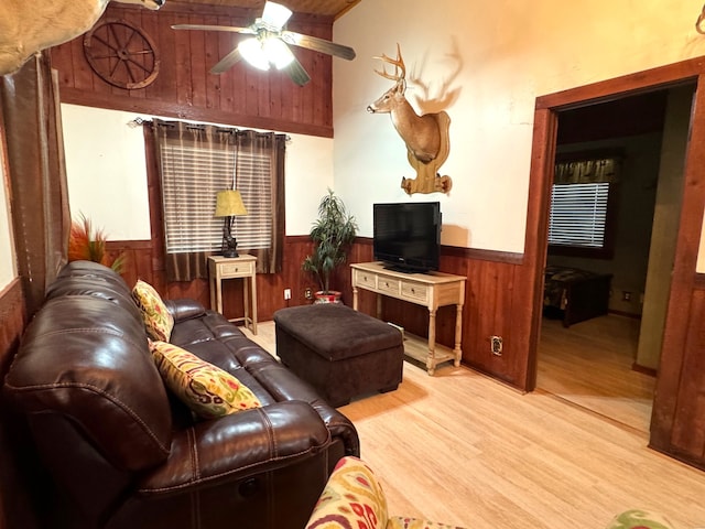 living room with hardwood / wood-style floors, ceiling fan, and wood walls