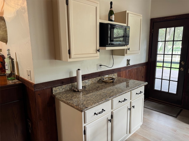 kitchen with stone counters, light wood-type flooring, and white cabinetry