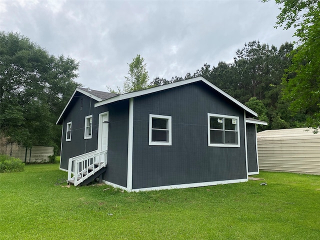 view of side of home featuring a lawn and an outdoor structure