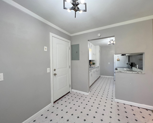 interior space with light floors, baseboards, electric panel, ornamental molding, and white cabinets