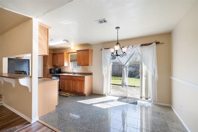 kitchen with an inviting chandelier, hardwood / wood-style floors, hanging light fixtures, sink, and a kitchen breakfast bar