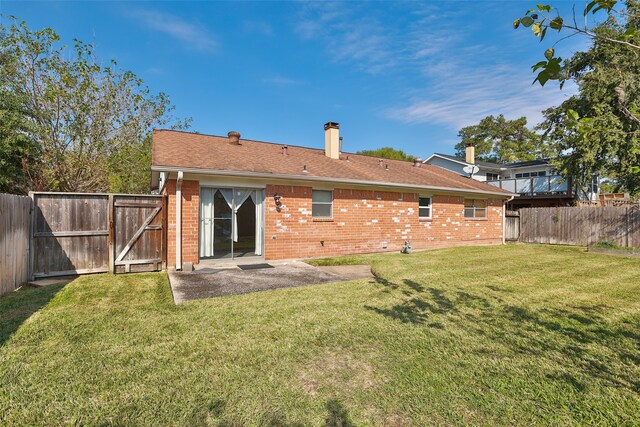 back of property featuring a patio area and a lawn