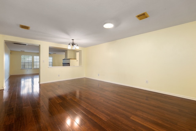 unfurnished living room featuring a notable chandelier and dark hardwood / wood-style floors