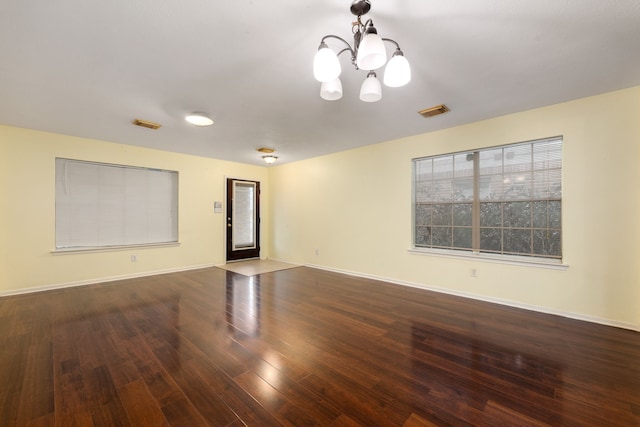 unfurnished room featuring dark hardwood / wood-style flooring and a chandelier