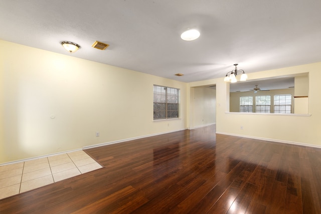 spare room with hardwood / wood-style floors and ceiling fan with notable chandelier