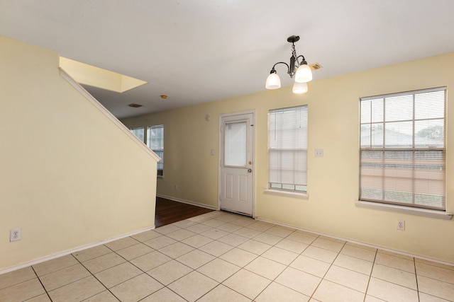 spare room featuring a chandelier, plenty of natural light, and light tile patterned floors