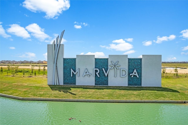 community / neighborhood sign featuring a water view, a lawn, and a rural view