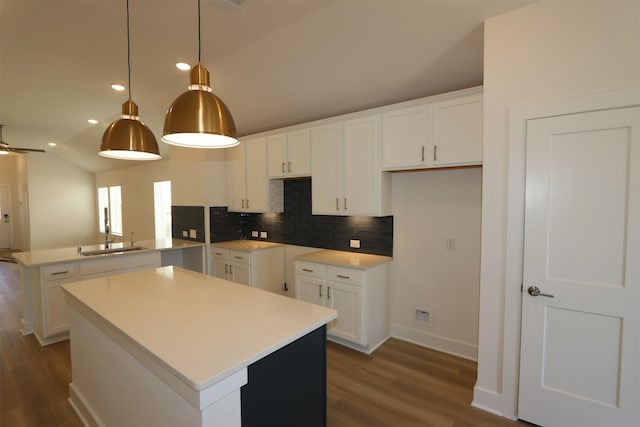 kitchen featuring backsplash, lofted ceiling, a peninsula, wood finished floors, and a sink